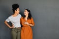 Two women friends embracing and laughing on grey background Royalty Free Stock Photo