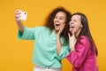 Two women friends european american girls in pink green clothes posing isolated on yellow background. People lifestyle Royalty Free Stock Photo