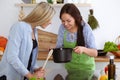 Two women friends looking into the dark pot and taste new recipes for delicious vegetarian soups while standing near the Royalty Free Stock Photo