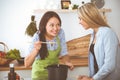 Two women friends looking into the dark pot and taste new recipes for delicious vegetarian soups while standing near the Royalty Free Stock Photo