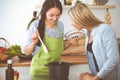 Two women friends looking into the dark pot and taste new recipes for delicious vegetarian soups while standing near the Royalty Free Stock Photo