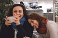 Two women friends enjoying a joke and a chat and a cup of coffee or tea, laughing and smiling in a cafe Royalty Free Stock Photo