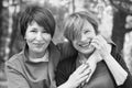 Two women friends 60s and 40s years hugging and walking in park Royalty Free Stock Photo