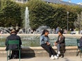 Women friends chat on the edge of the fountain in the Palais Royal garden, Paris, France