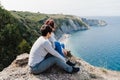 Two women friends sitting and looking at beautiful sea landscape on top of the mountain. Friendship and nature concept Royalty Free Stock Photo