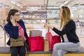 Two woman friends sitting in the mall after shopping, looking bags, resting. Royalty Free Stock Photo