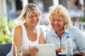Two women friends using tablet PC in outdoor cafe Royalty Free Stock Photo