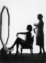 Two women in front of a large mirror