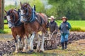 Two women guide a plow pulled by draft horses