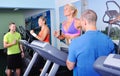 Two women in gym exercising with personal fitness trainer