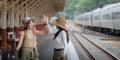 Two women are happy while traveling at the train station. tour concept. Two asian women best friend travel high five on