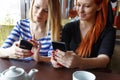 Two women having fun at the cafe and looking at smart phone.