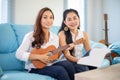 Two women are having fun playing ukulele and smiling at home for relax time Royalty Free Stock Photo
