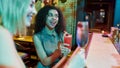 Two women having fun, toasting, drinking cocktails while sitting at the bar counter. Friends spending time at night club Royalty Free Stock Photo