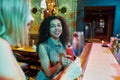 Two women having fun, toasting, drinking cocktails while sitting at the bar counter. Friends spending time at night club Royalty Free Stock Photo