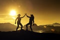 Two women high five on a mountaintop