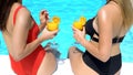 Two women holding cool fresh beverages at poolside on summer day, back view Royalty Free Stock Photo