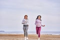 Two women are jogging along the sandy bank of a large river. Women do gymnastics