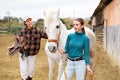 Two women jokey preparing horse for riding in paddock