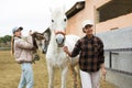 Two women jokey preparing horse for riding in paddock