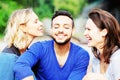 Two women kissing handsome man on his cheeks