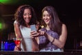 Two women looking at mobile phone and smiling at bar counter Royalty Free Stock Photo