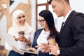 Two women and a man are drinking coffee and watching something on the laptop screen. Royalty Free Stock Photo