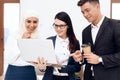 Two women and a man are drinking coffee and watching something on the laptop screen. Royalty Free Stock Photo