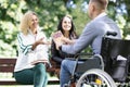 Two women and a man in a wheelchair are learning English while sitting in park Royalty Free Stock Photo