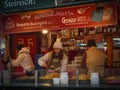 People work behind the counter with a shopsign in Christmas fair kiosk, selling roasted potatoes in Vienna, Austria