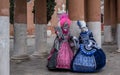Two women in masks and ornate blue and pink costumes at Venice Carnival Royalty Free Stock Photo