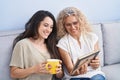 Two women mother and daughter drinking coffee looking picture at home Royalty Free Stock Photo