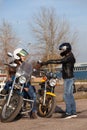 Two women motorcyclists exchange greetings with safety fists touching in leather glothes