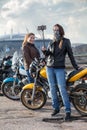 Two women motorcyclists making photo with selfie stick and front camera of cellular