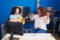 Two women musicians playing classical guitar and violin at music studio Royalty Free Stock Photo