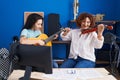 Two women musicians playing classical guitar and violin at music studio Royalty Free Stock Photo