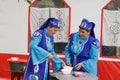 Two women in national Tatar clothes pours soup into plates for guests of the holiday. Day of the Siberian village of New Yurts