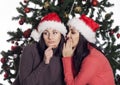 Two women near christmas tree gossip