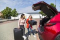 Two women packing luggage in car trunk for trip Royalty Free Stock Photo