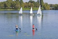 Two women on paddle board and three boat sailling