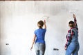 Two women painting new apartment walls in color white with paint roller. Renovating home