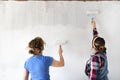 Two women painting new apartment walls in color white with paint roller. Renovating home