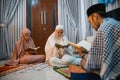 two women participants read the Quran following male recitation leader