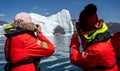 Two women photographing Hurtigruten`s MS Fridtjof Nansen from a zodiac through an arch in a large iceberg at Disko Bay, Greenland Royalty Free Stock Photo