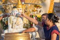 Two women pouring water over Buddha statue Royalty Free Stock Photo