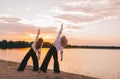 Two women practicing yoga meditation at sunrise. Morning yoga on the beach or coast of river