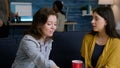 Two women relaxing on sofa drinking beer while socializing during home party Royalty Free Stock Photo