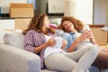 Two Women Relaxing On Sofa With Hot Drink In New Home Royalty Free Stock Photo