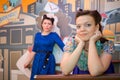 Two women in retro-style dresses at bar with art