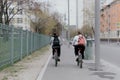 Two women ride bicycles on the sidewalk